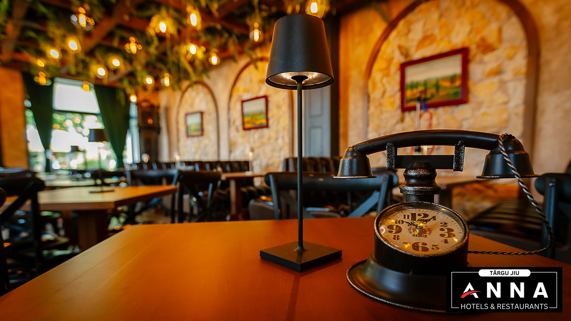Detaliu de masă: lampă neagră și un telefon vechi cu ceas, cu sala de piatră și arcade în fundal